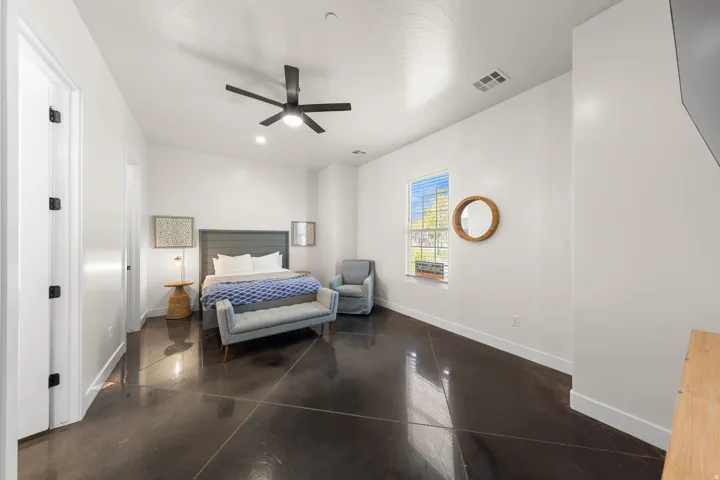 Polished concrete flooring, contemporary ceiling fan, recessed lighting, white walls, and a window providing natural light