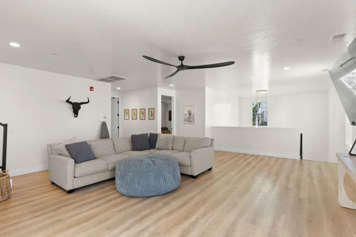 Light wood-finish flooring throughout, complemented by a contemporary black ceiling fan and recessed lighting