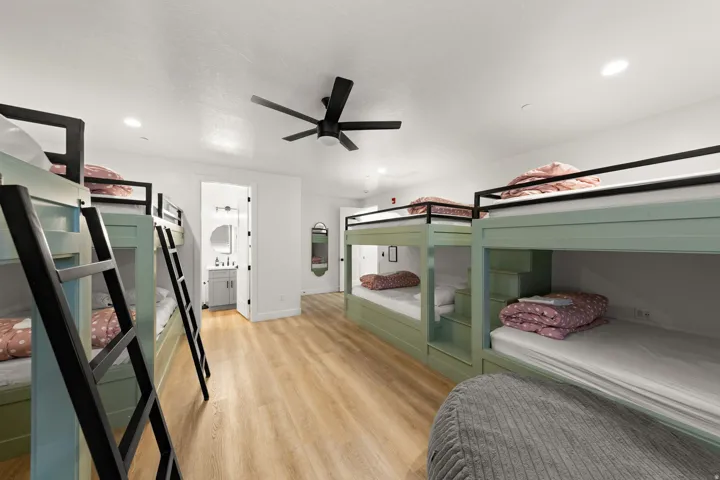 Light wood-finish flooring, recessed lighting, and a black ceiling fan illuminate the space