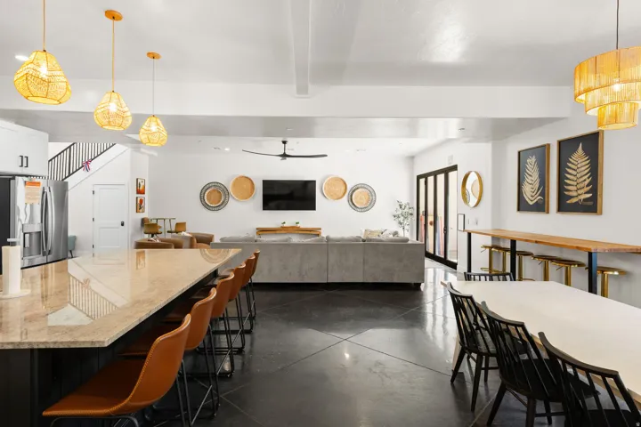 Long granite-style countertop, dark flooring, built-in stainless steel refrigerator, and black framed sliding glass doors
