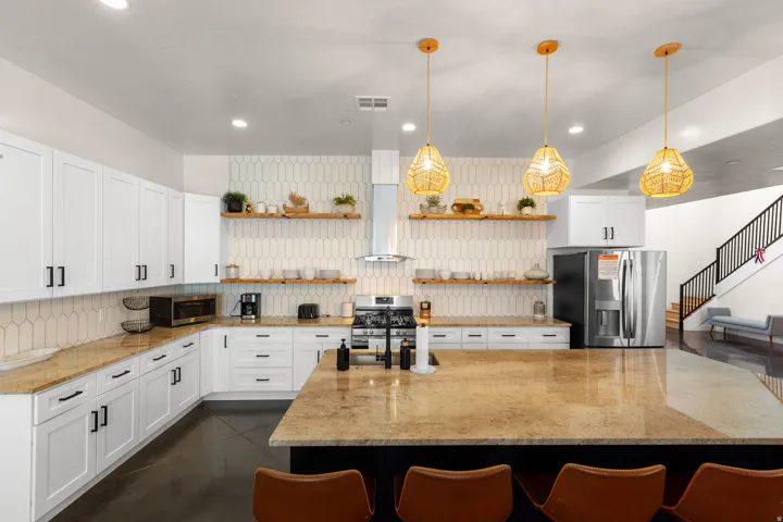White cabinetry with black hardware, stone countertops, and a full-height geometric tile backsplash
