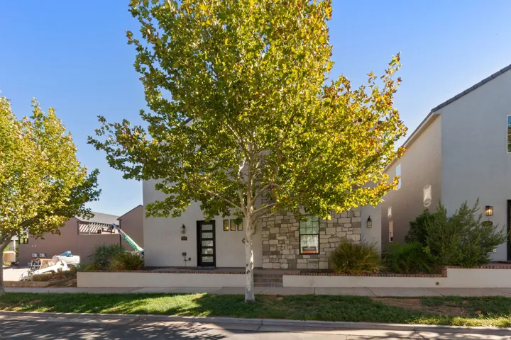 Stucco and stone exterior with a modern entry door, front landscaping, and a concrete pathway