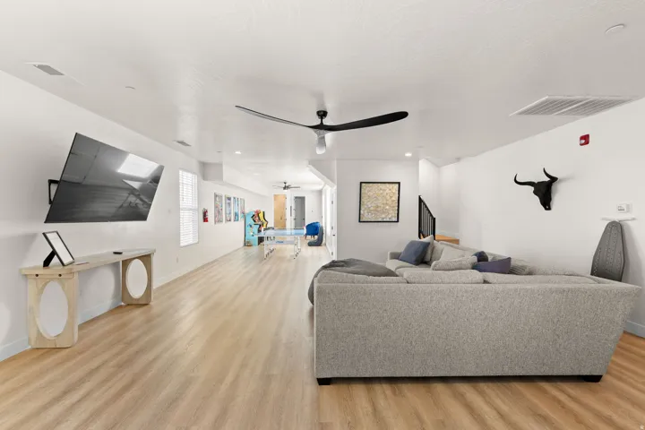 Spacious open-concept room featuring light wood-finish flooring, recessed lighting, and a contemporary ceiling fan
