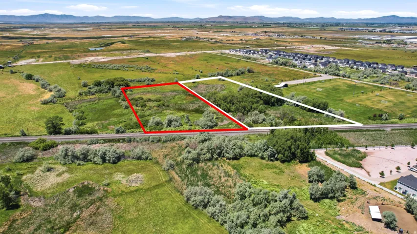 Expansive land parcel featuring natural vegetation and proximity to a developed residential area