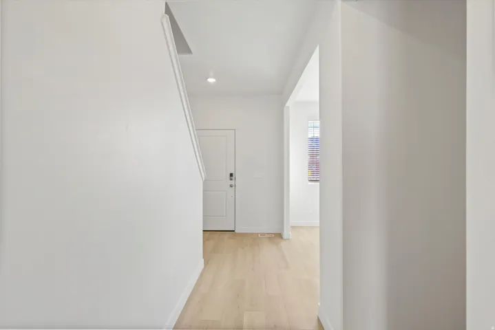 **DISCLAIMER** Interior package may vary. Light wood-finish flooring, white walls, recessed lighting, and a contemporary entry door with smart lock