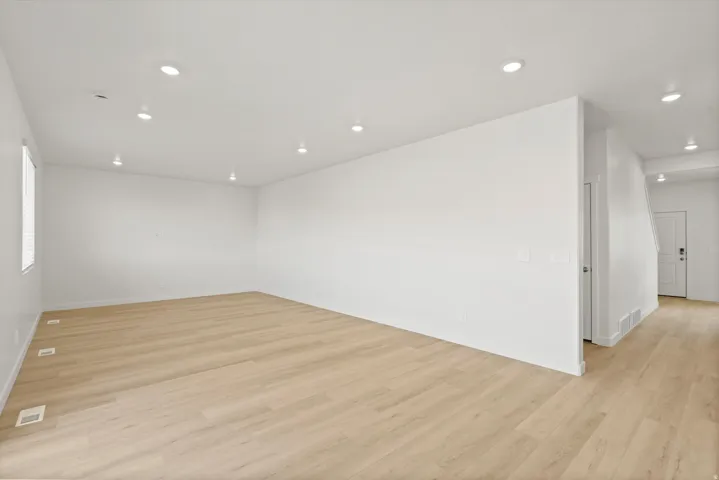 **DISCLAIMER** Interior package may vary. Expansive open-concept room featuring wood-finish flooring, recessed lighting, and bright white walls