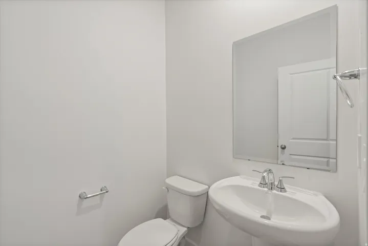 **DISCLAIMER** Interior package may vary. Pedestal sink with polished chrome hardware, rectangular wall-mounted mirror, and white toilet