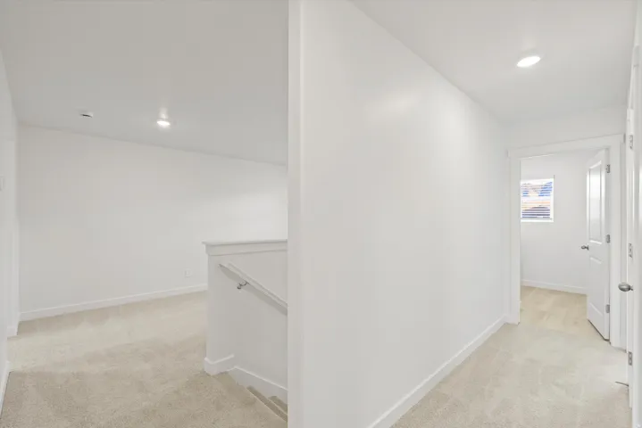 **DISCLAIMER** Interior package may vary. Neutral-toned carpeting, recessed ceiling lighting, white painted walls, white banister with handrail, and white paneled doors