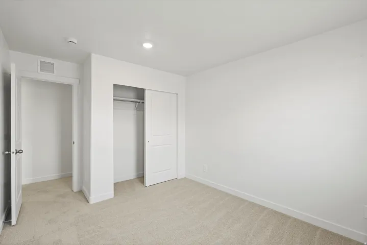 **DISCLAIMER** Interior package may vary. Recessed lighting, light-toned carpet flooring, white walls, white trim, and a white sliding closet door