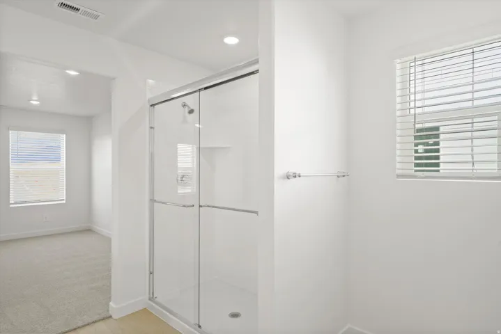**DISCLAIMER** Interior package may vary. Glass-enclosed shower with a sliding door, chrome shower fixtures, and a recessed soap niche