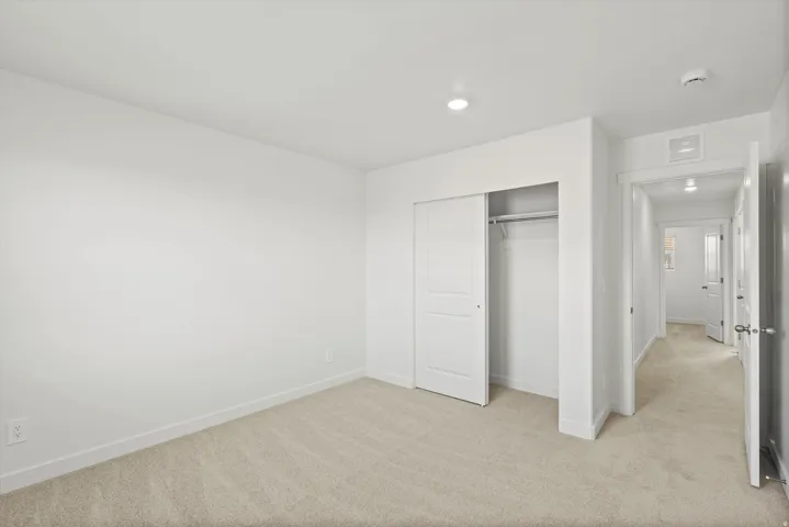 **DISCLAIMER** Interior package may vary. Neutral carpet flooring, white walls, recessed ceiling lighting, and sliding closet doors