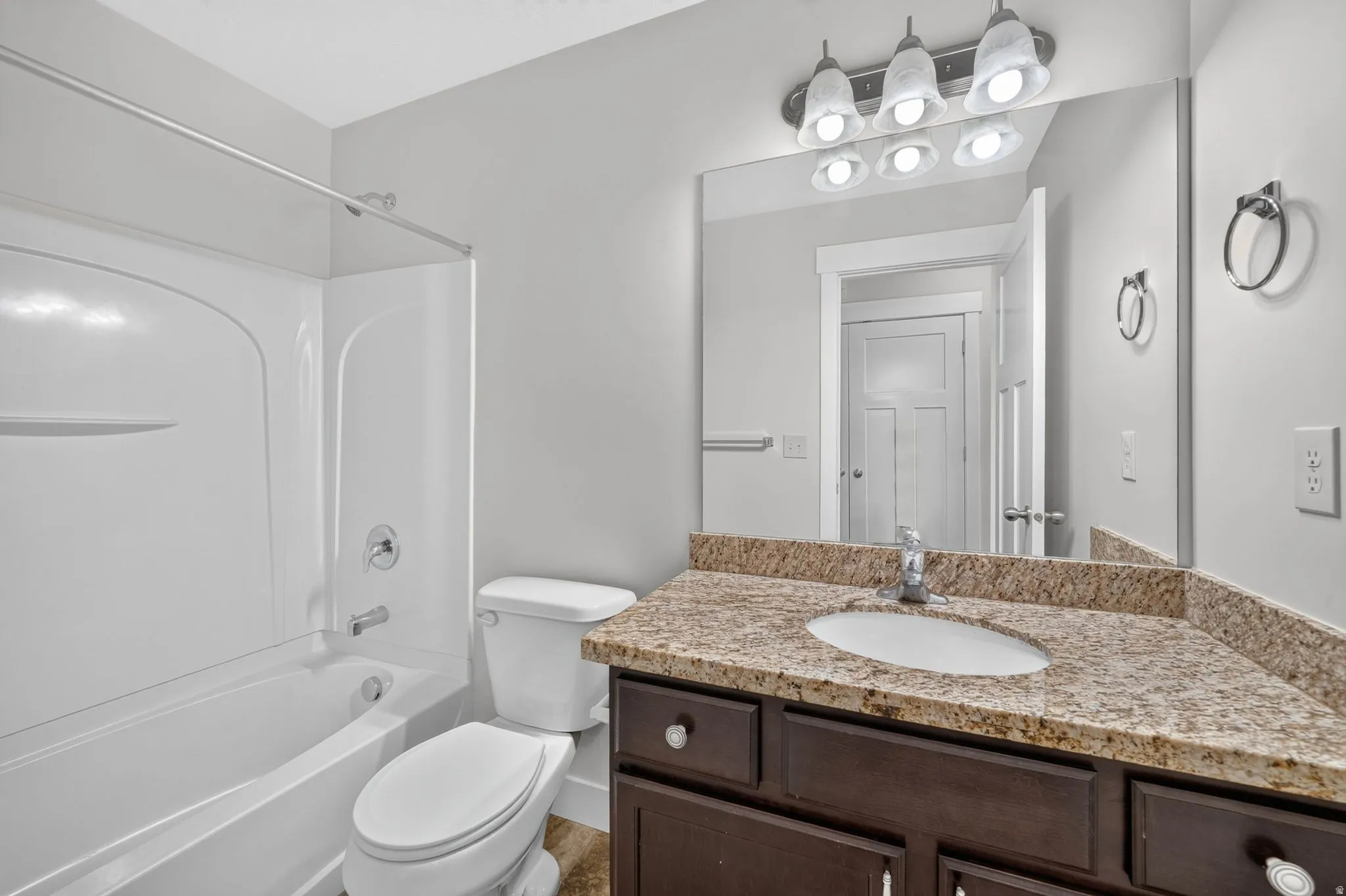 Built-in vanity with a granite-style countertop, undermount sink, and dark wood-finish cabinetry