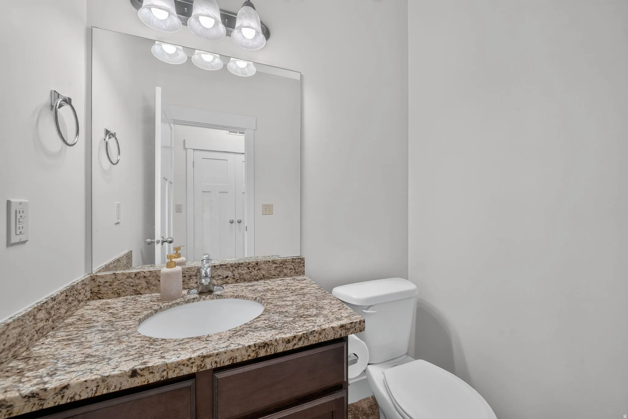 Vanity with a granite-style countertop, undermount sink, and dark wood-finish cabinetry