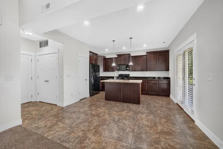 Open-concept kitchen with dark wood cabinetry, a central island, and stone countertops