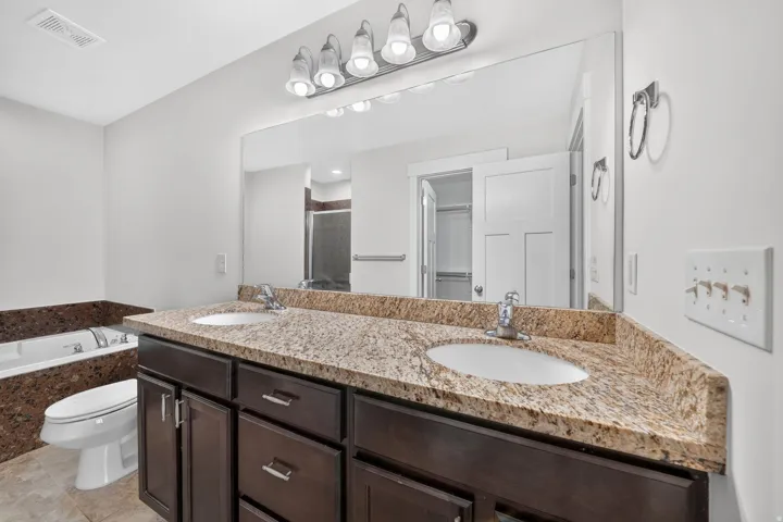 Dual vanity with a stone countertop, dark wood-finish cabinetry, and undermount sinks