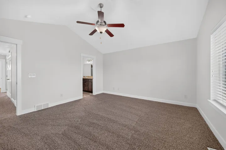 Vaulted ceiling with a ceiling fan, carpeted flooring, and window blinds