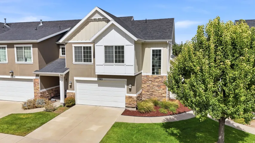 Contemporary exterior with stone facade accents, two-car garage, and established landscaping