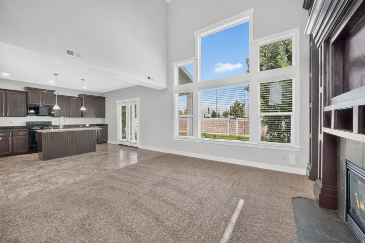 Vaulted ceiling, expansive window array, built-in fireplace, kitchen island with sink, and dark wood-finish cabinetry