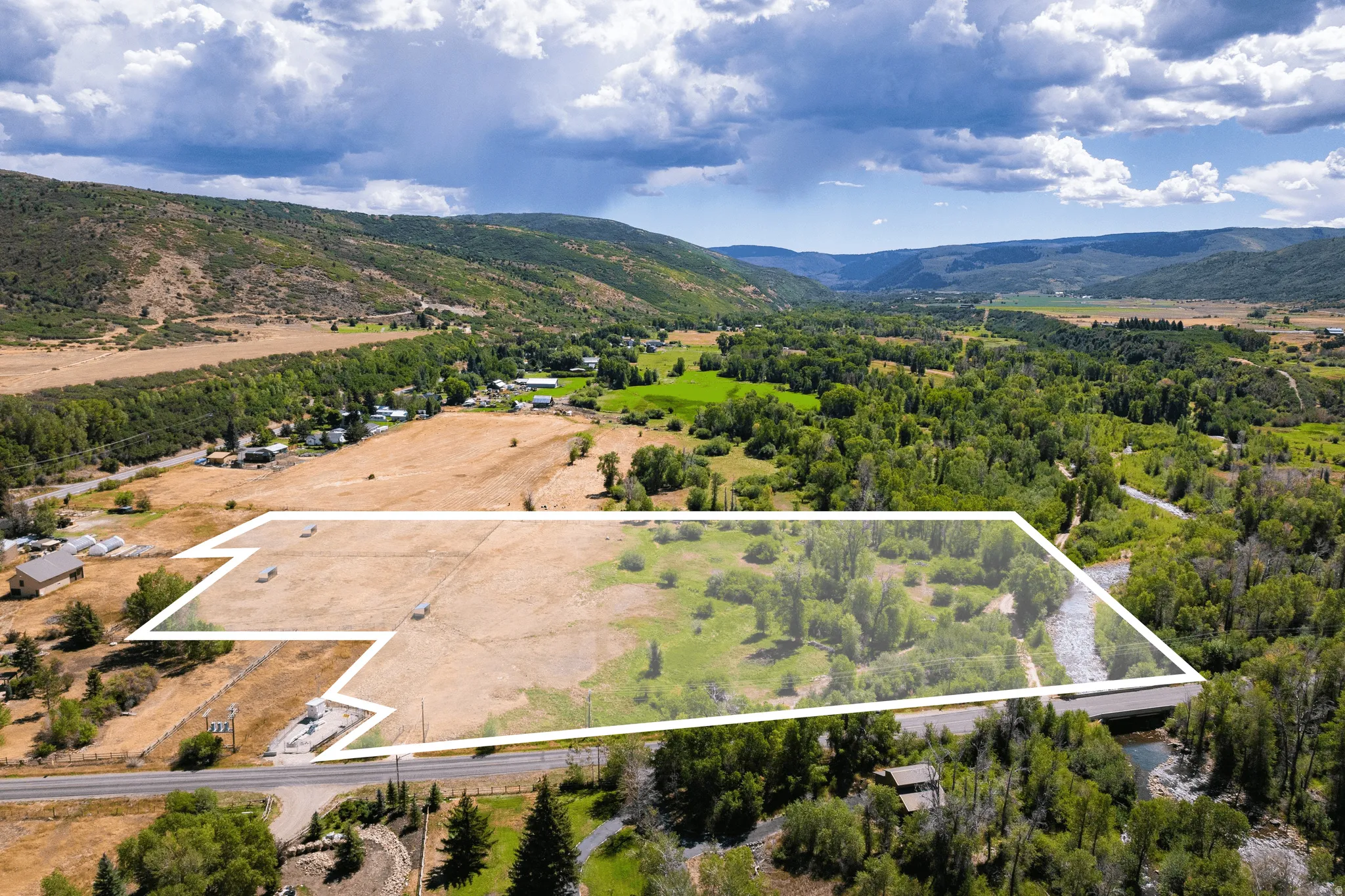 Expansive acreage featuring a natural watercourse, mature trees, and mountainous topography