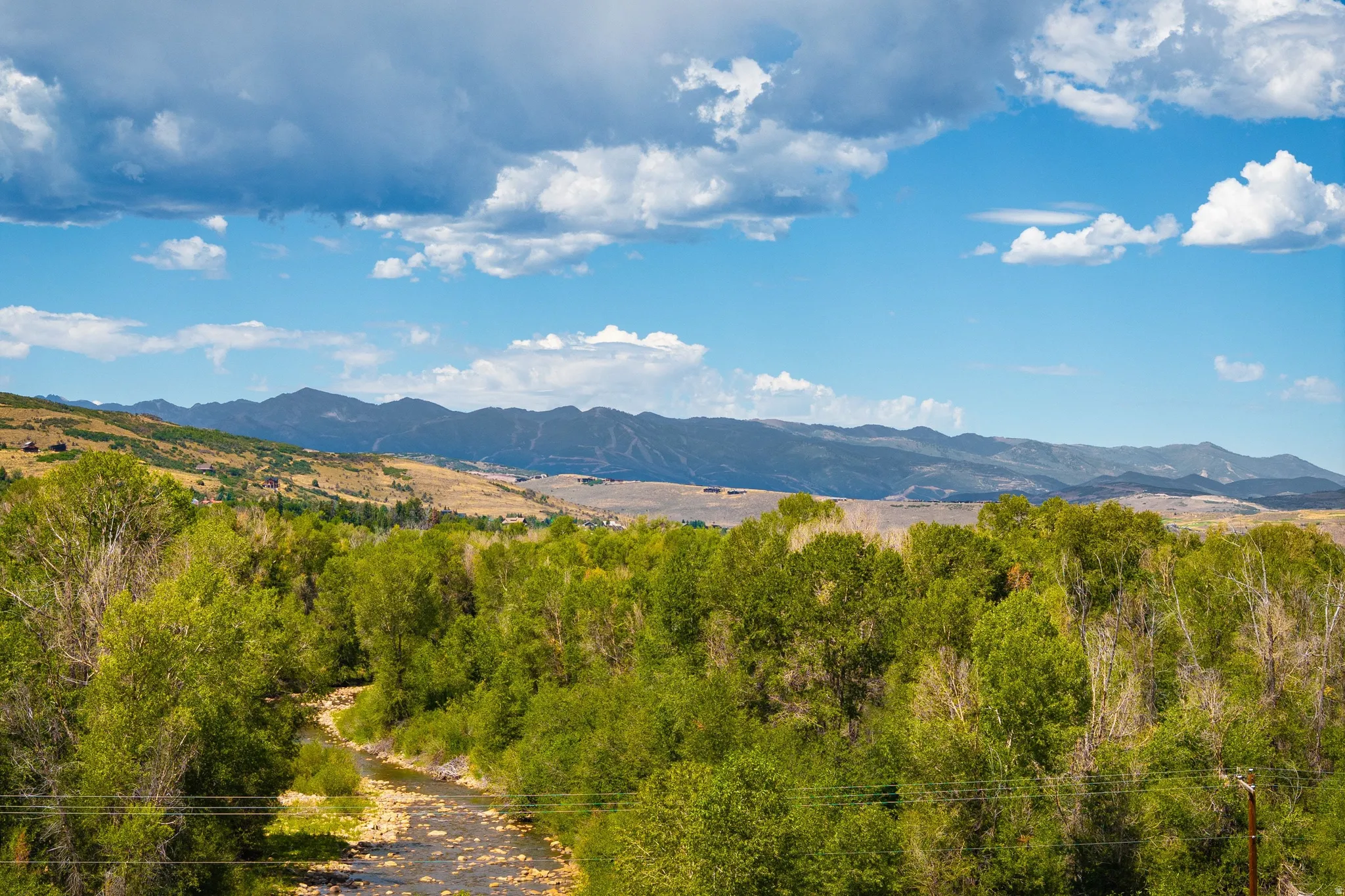 Mountainous landscape with expansive sky, a winding river, and abundant green trees