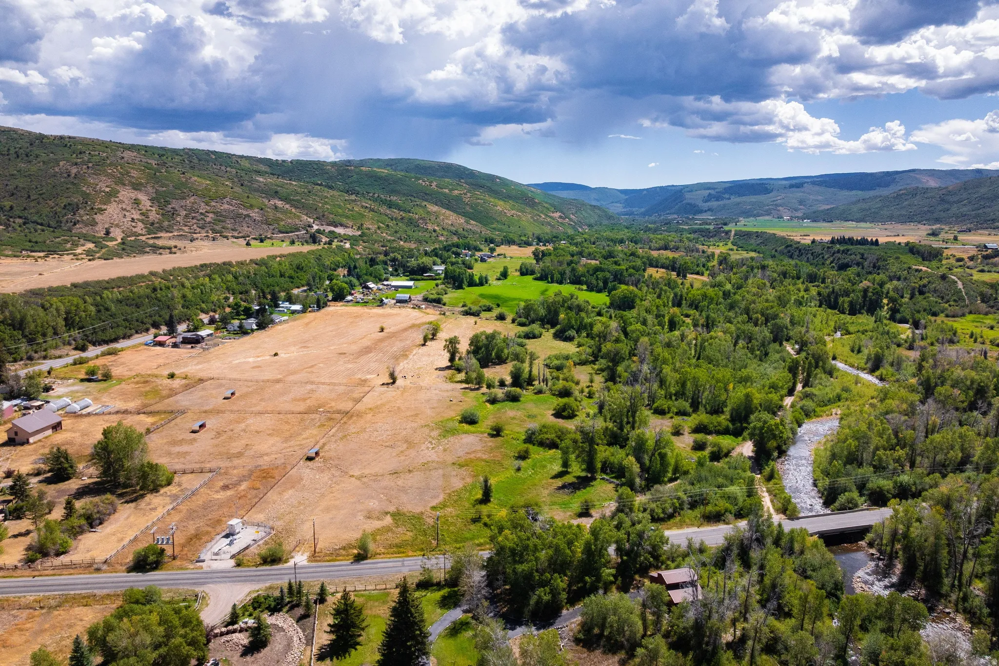 Expansive property featuring a winding river, dense tree lines, open fields, and mountainous terrain