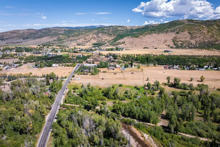 Expansive property featuring rural landscape, distant mountain backdrop, a prominent paved road, a river, and substantial mature trees