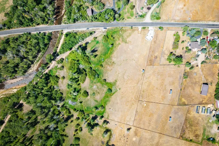 Expansive property featuring varied terrain, a winding river, and a paved roadway