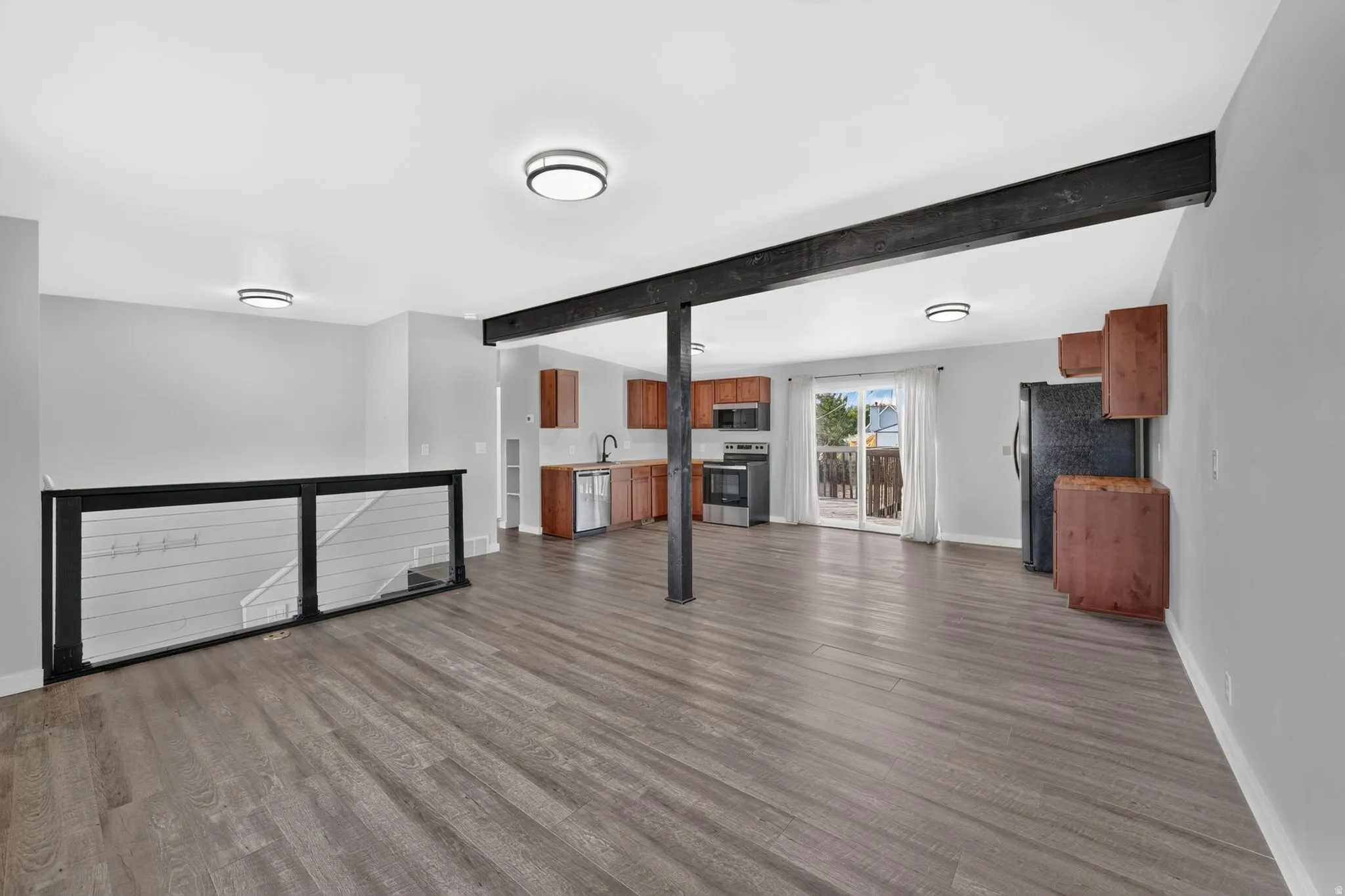 Open concept living area featuring wood-finish flooring, a kitchen with wood-finish cabinetry, and a sliding glass door