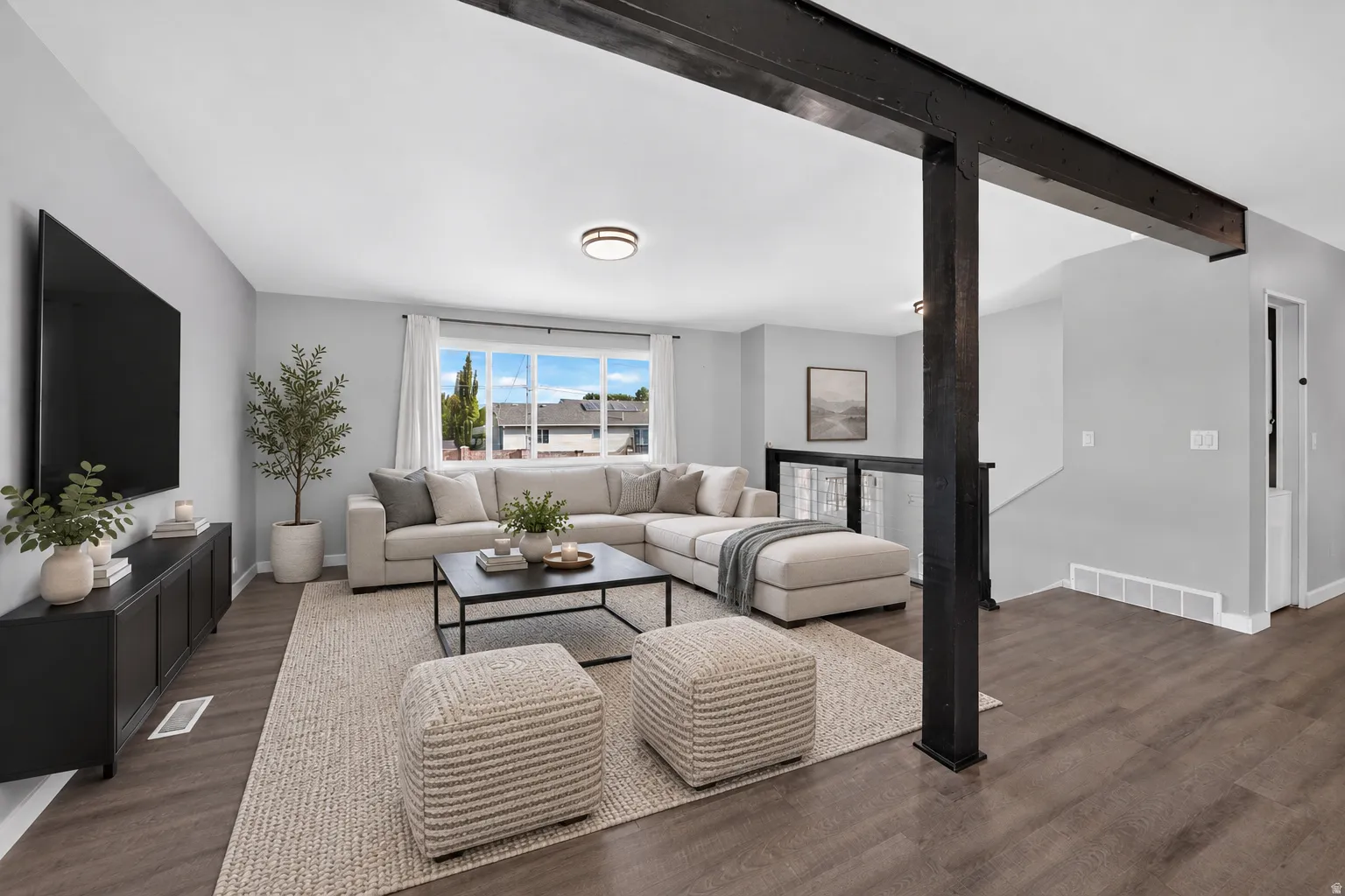 Virtually Staged Image. Open-concept living space featuring wood-finish flooring, a large window, recessed lighting, and a prominent structural beam