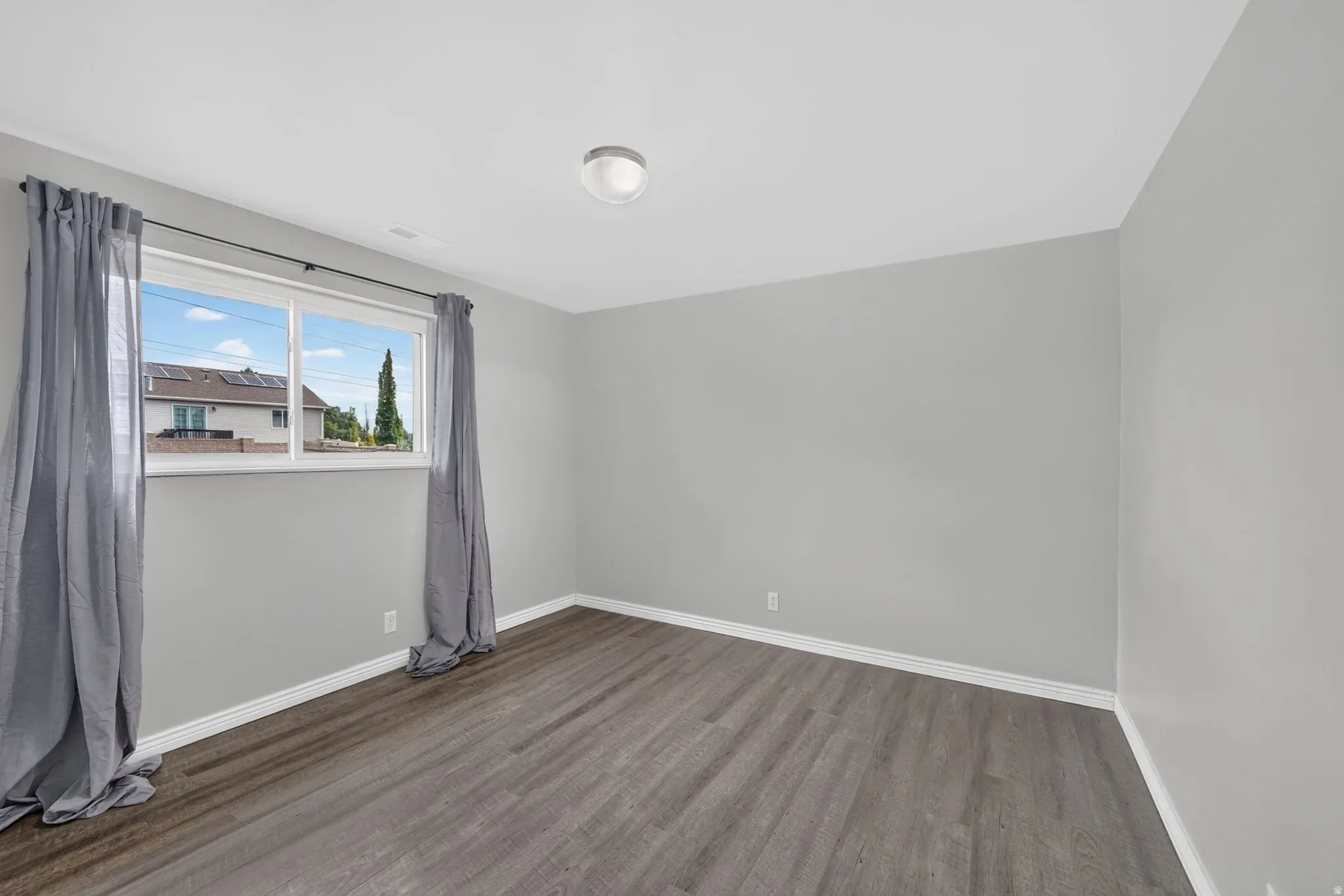Wood-finish flooring, light gray walls, white trim, and a flush-mount ceiling light