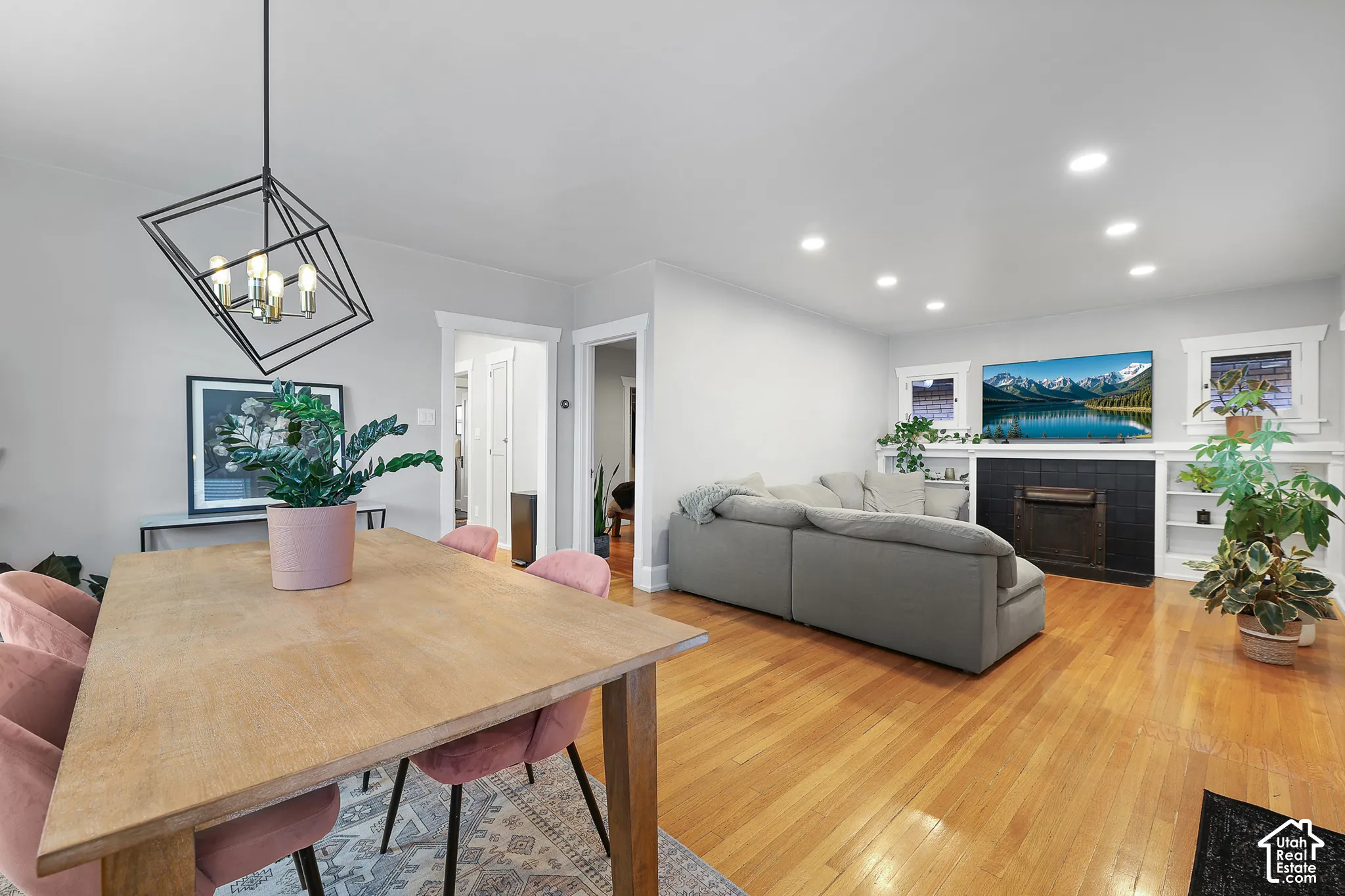 Newly installed recessed lighting, wood-finish flooring, built-in shelving, black tile fireplace surround