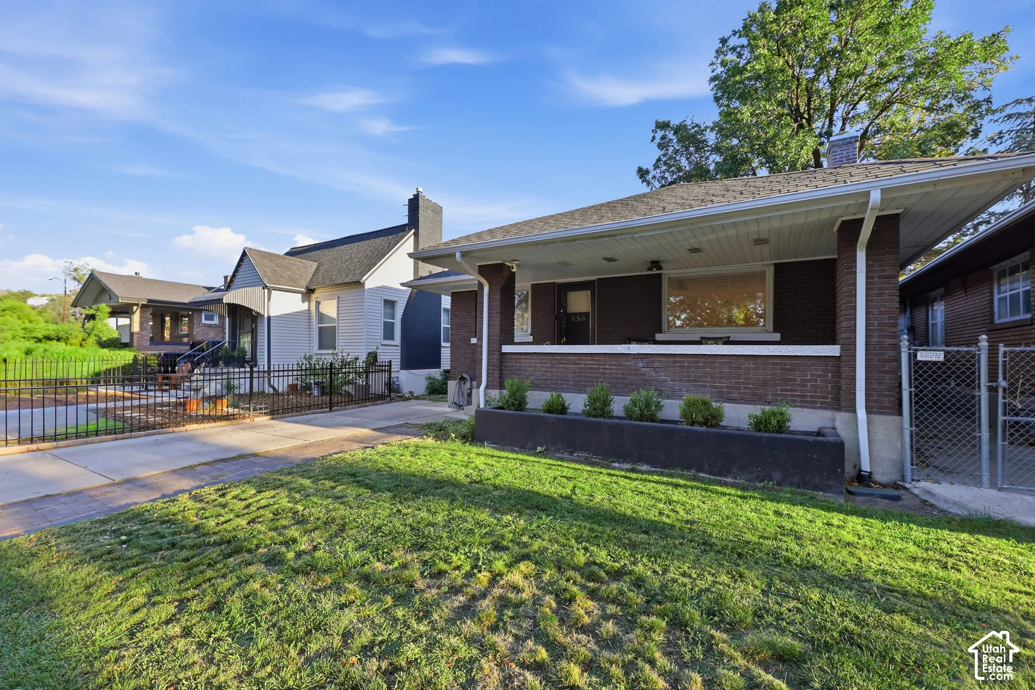 Brick exterior with covered front porch, white soffit, and front yard landscaping
