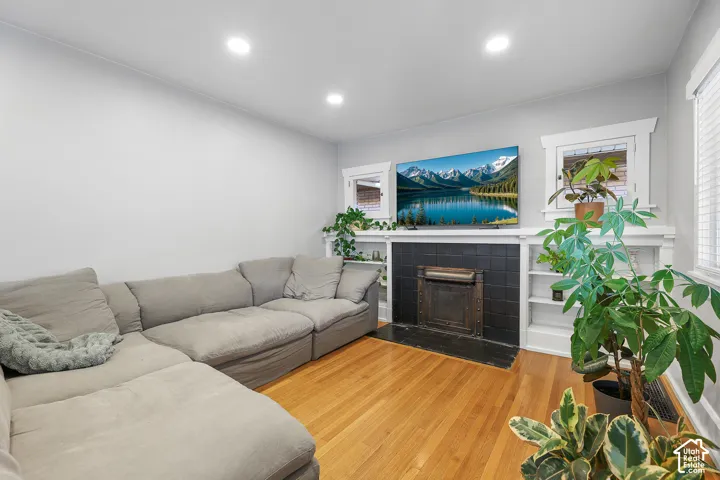 Newly installed recessed lighting, wood flooring, black tile fireplace surround, and built-in shelving