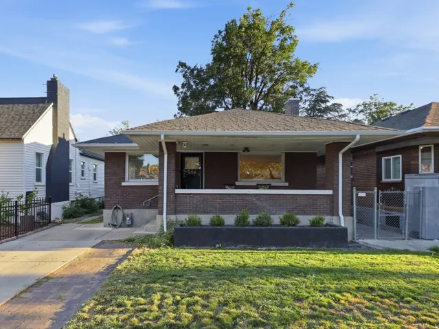 Brick exterior with a covered porch, established lawn, and a paved driveway