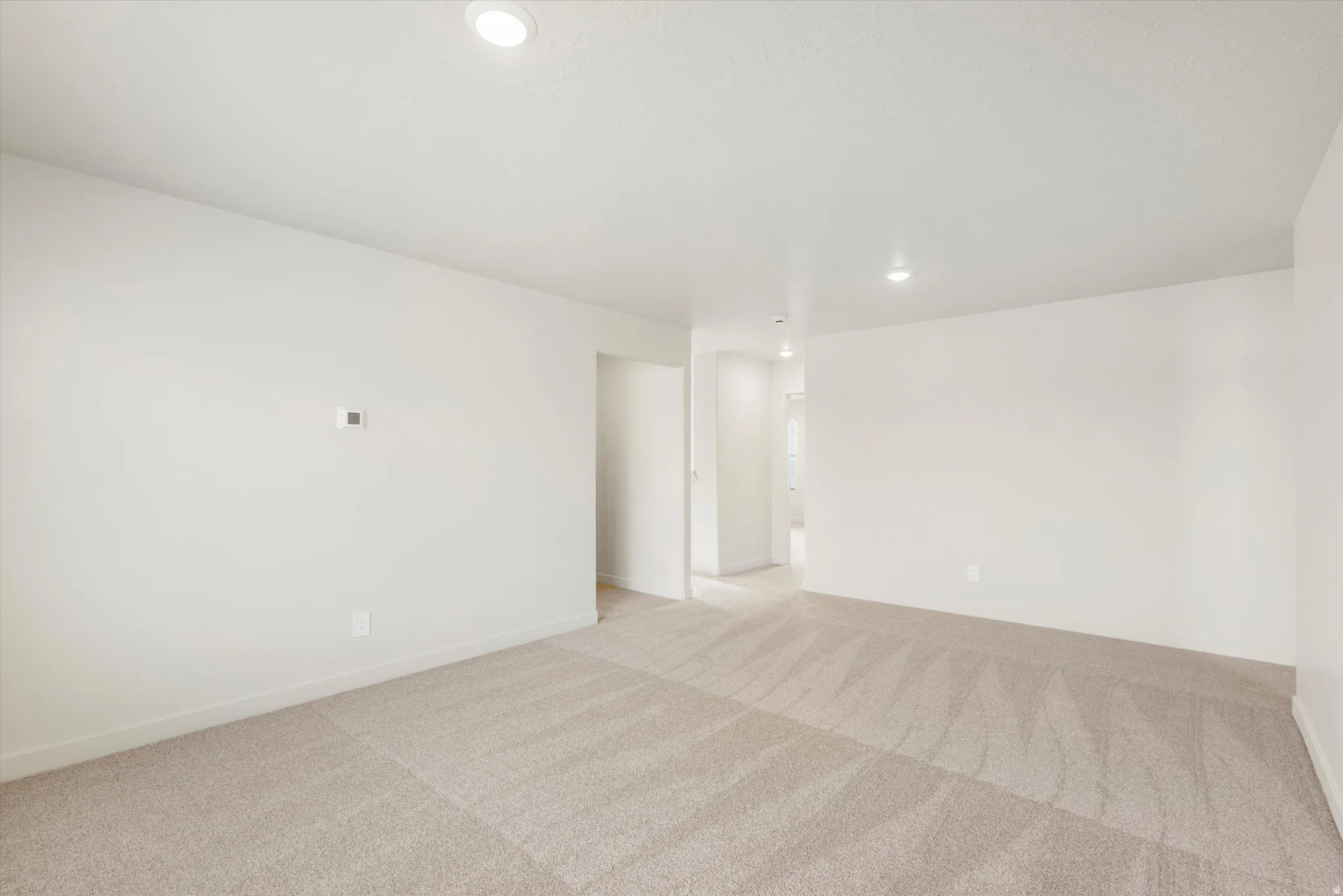 Expansive carpeted area with recessed lighting and neutral wall finishes
