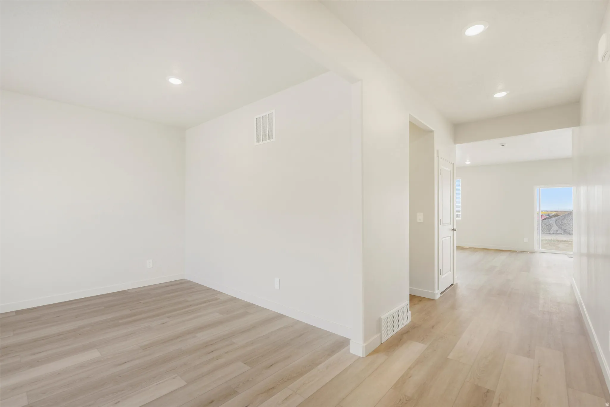 Wood-finish flooring throughout, recessed lighting, and bright white walls