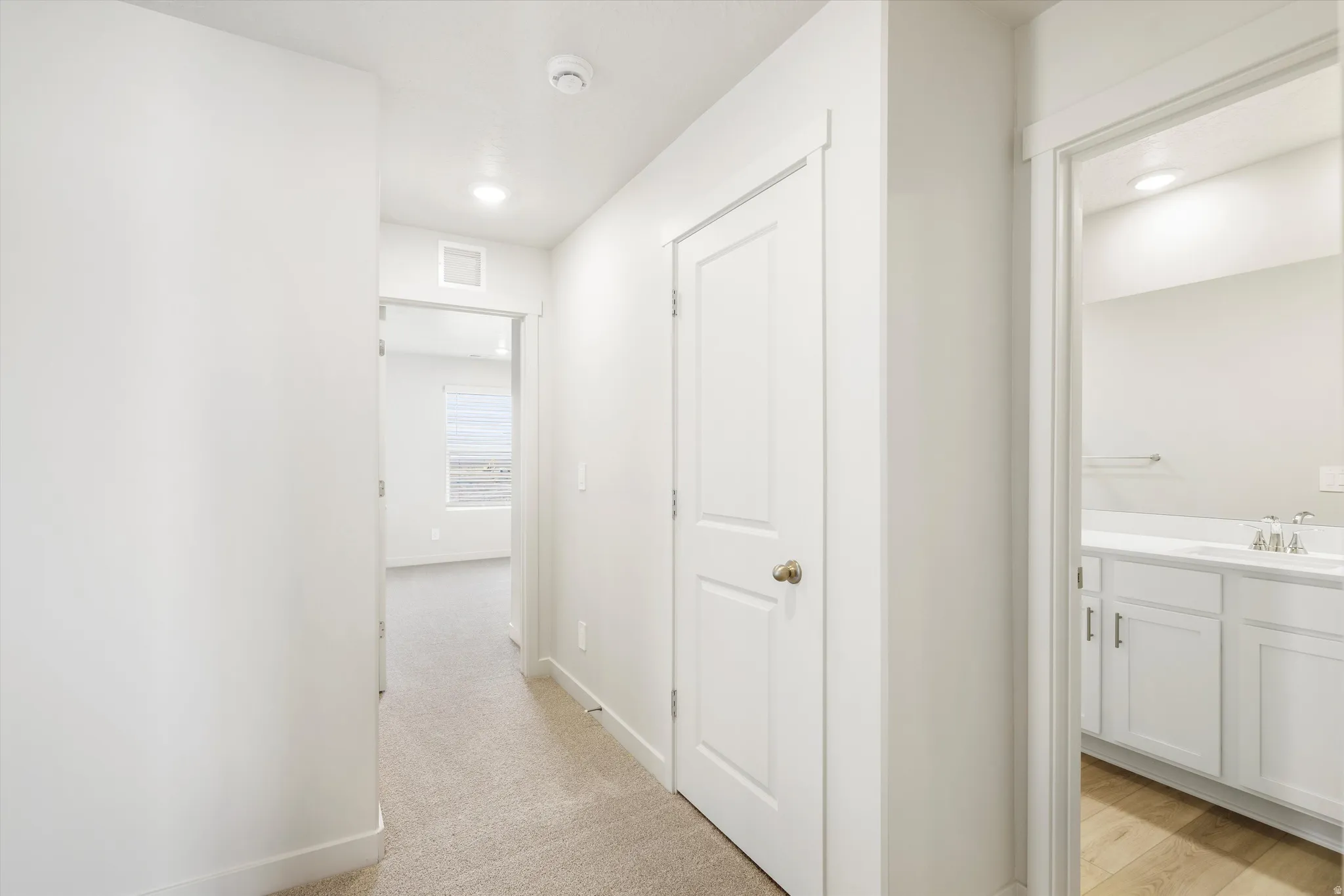 Hallway with neutral carpeting and recessed lighting