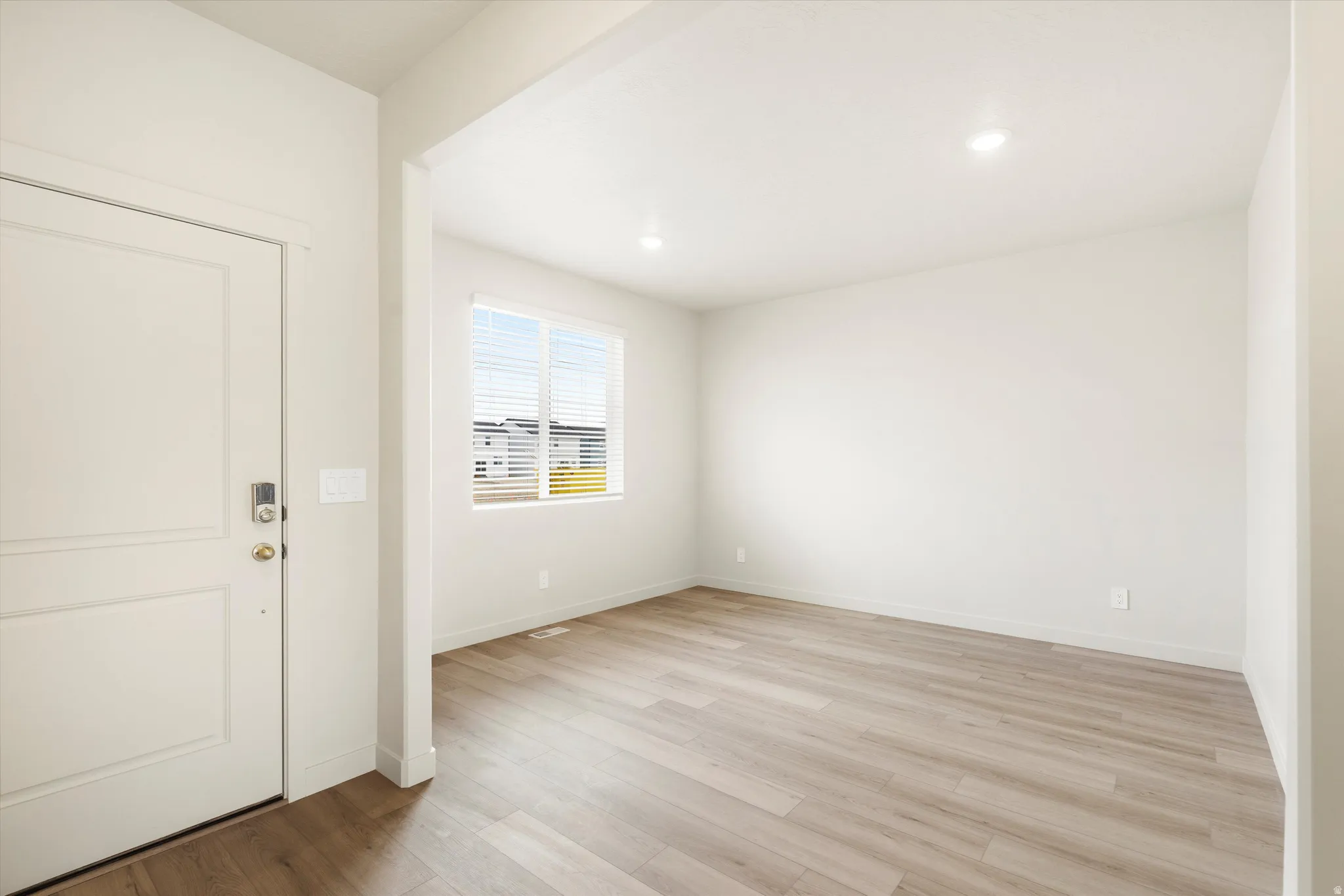 Recessed lighting illuminates the room with wood-finish flooring and a window offering natural illumination