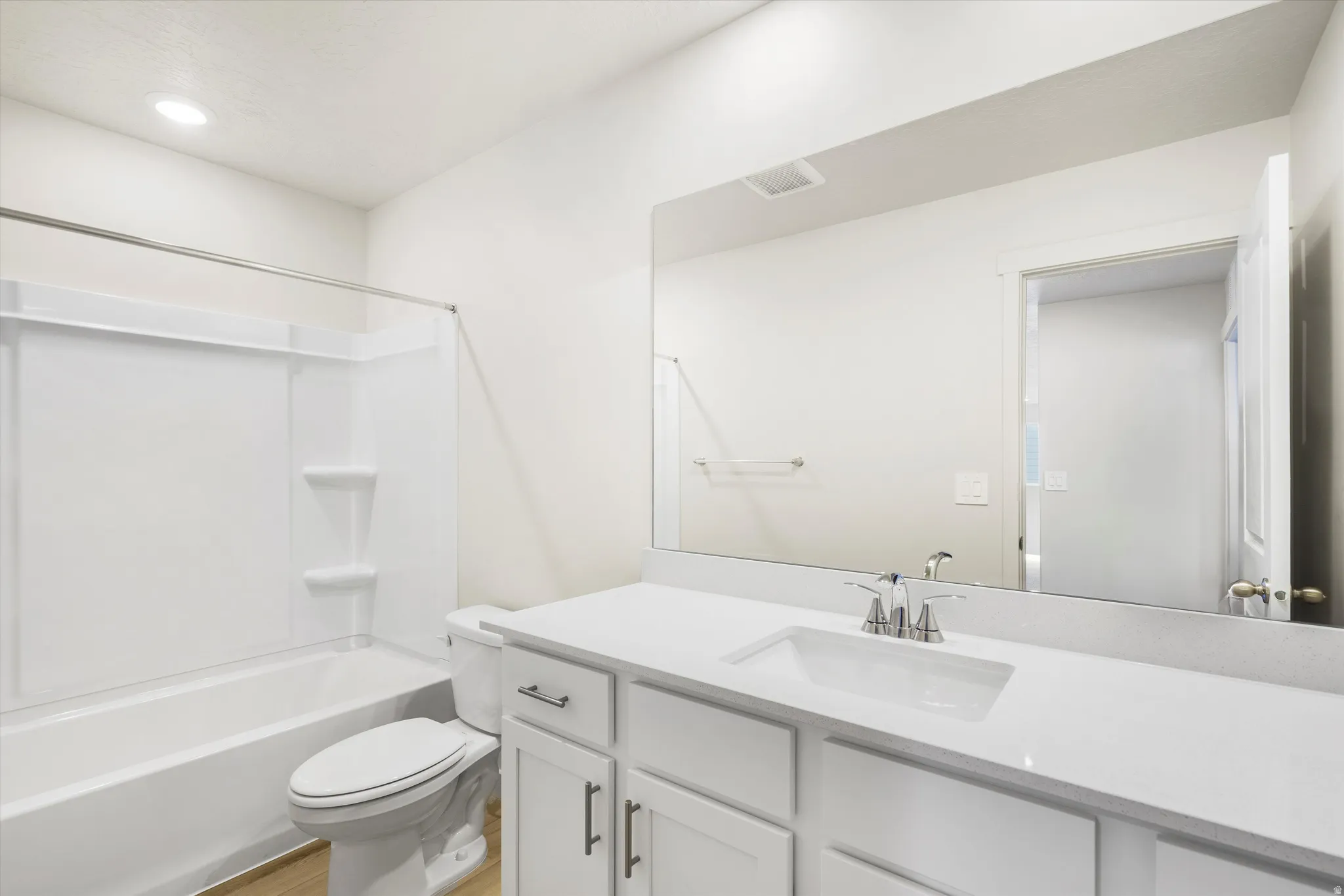 White vanity with a single basin sink, chrome faucet, and expansive wall-mounted mirror