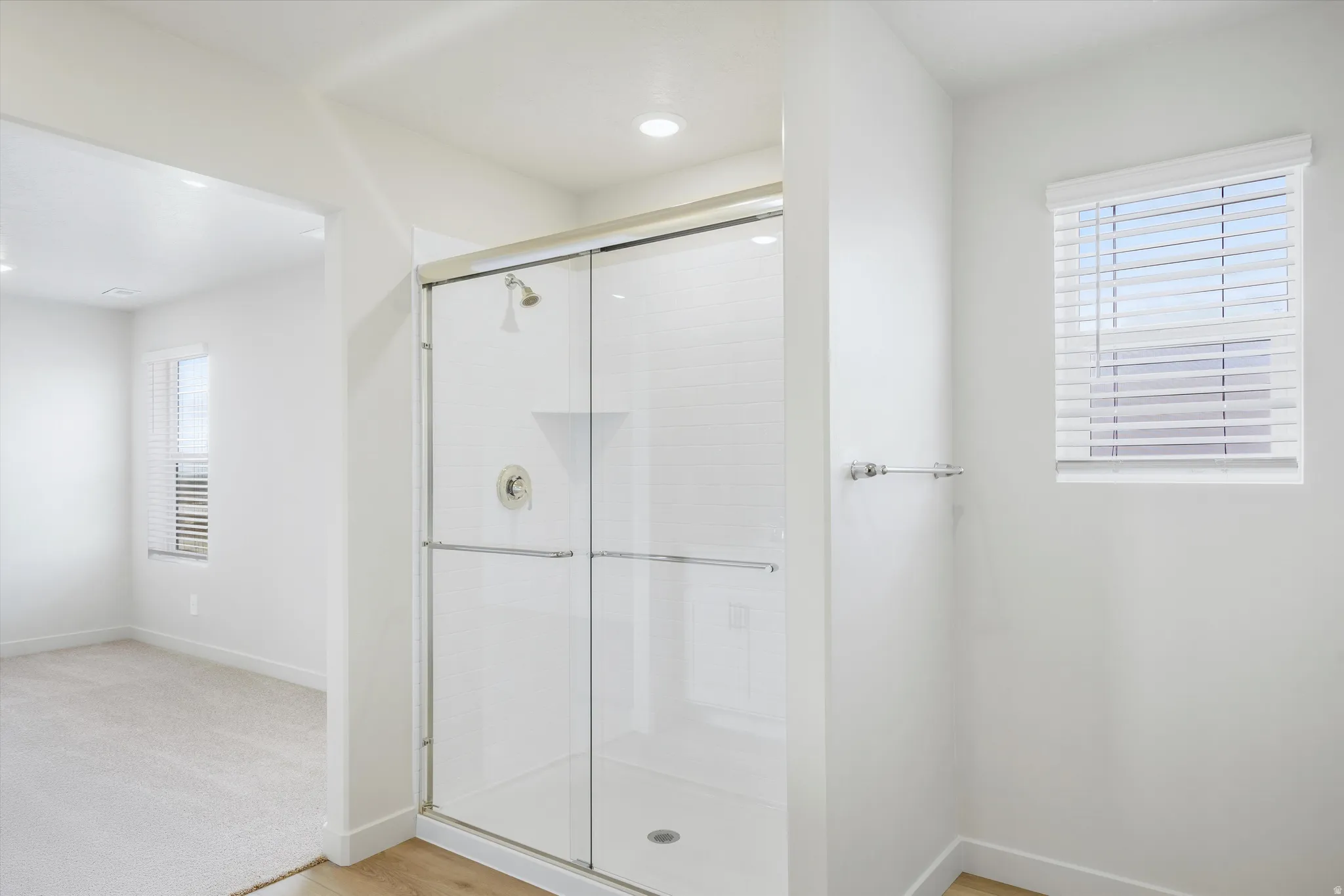 Full standing shower with clear glass enclosure, white subway tile surround, recessed lighting, and chrome fixtures