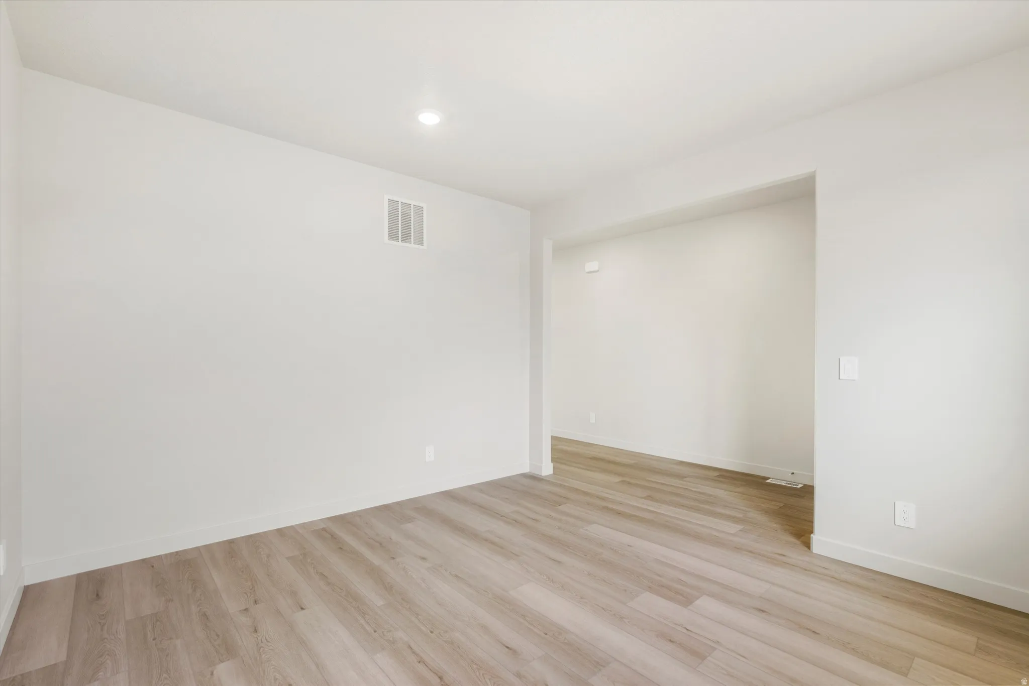 Recessed ceiling lighting, light wood-finish flooring, white walls, and a wide entryway