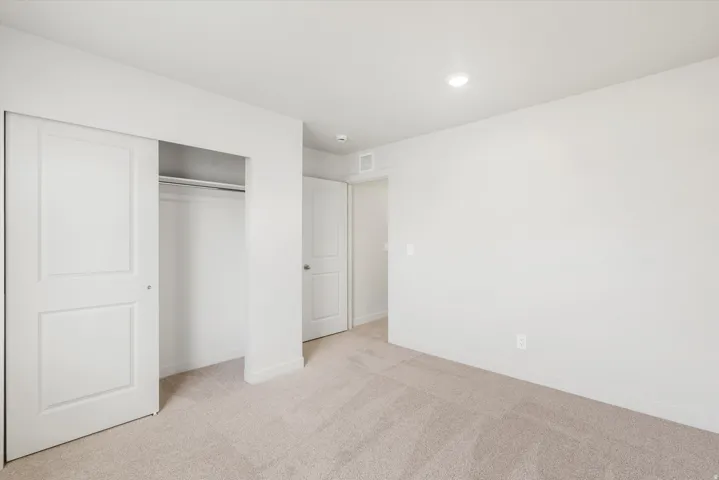 Recessed ceiling lighting, light-toned carpeting, white walls, and white paneled sliding closet doors