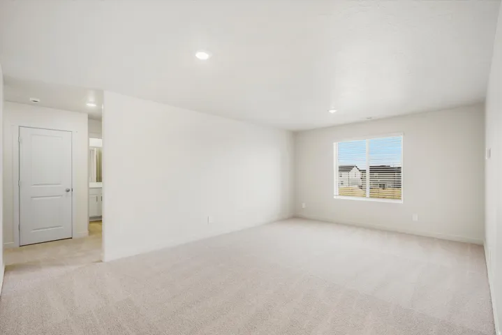 Spacious room with carpet flooring, a large window, recessed lighting, and a neutral color palette