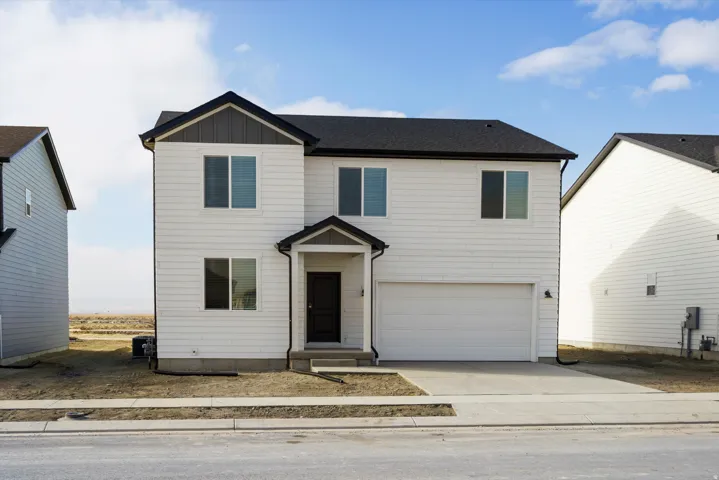 Two-story residence featuring white horizontal siding and dark vertical accent siding, a two-car garage with a concrete driveway, and a covered entry