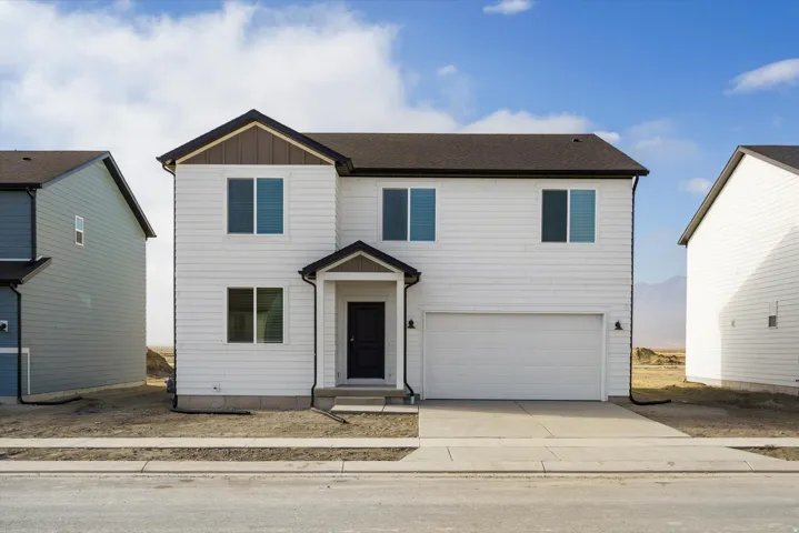 Two-story white siding residence featuring a dark roof, attached garage, and a covered entry porch