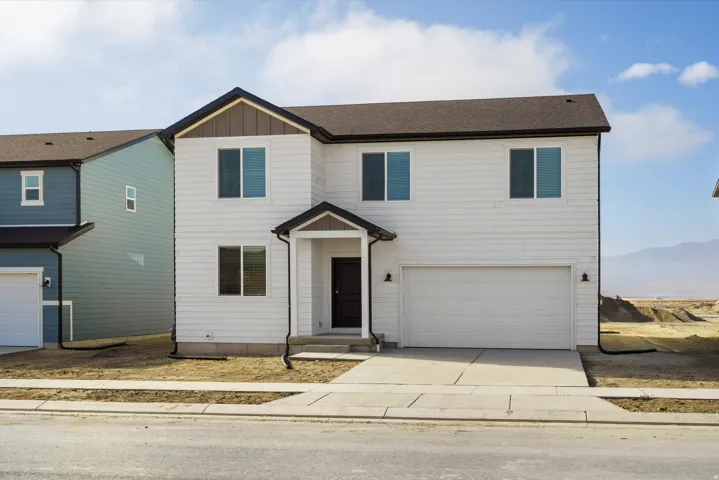 Two-story residence with white siding, dark brown roof, and an attached two-car garage
