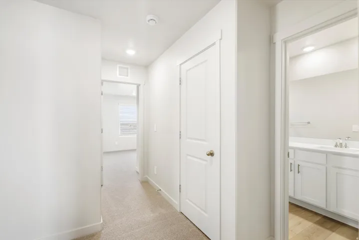 Hallway with neutral carpeting and recessed lighting