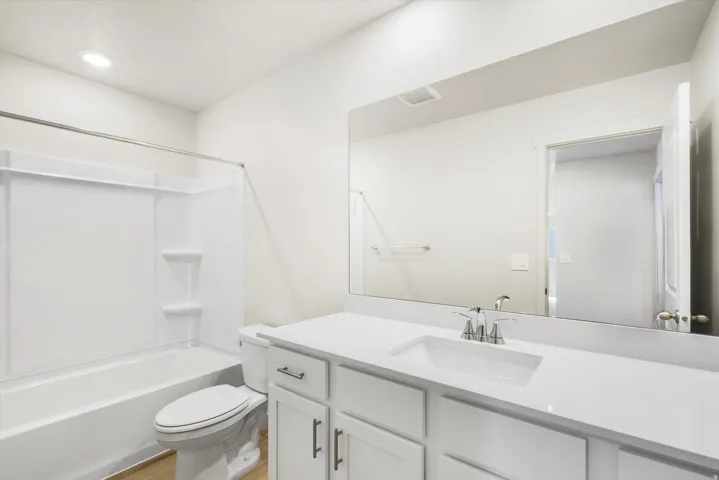 White vanity with a single basin sink, chrome faucet, and expansive wall-mounted mirror