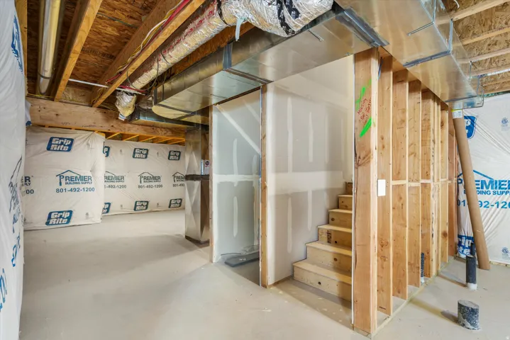 Unfinished lower level featuring exposed wood framing, concrete flooring, and exposed ceiling joists