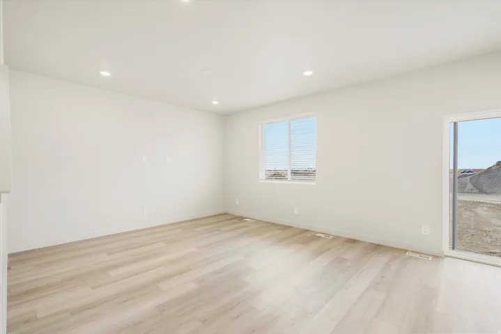 Recessed lighting, light-toned wood-finish flooring, white walls, double-pane window, and a glass sliding door